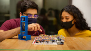 A male and female student in a work session looking at circuitry